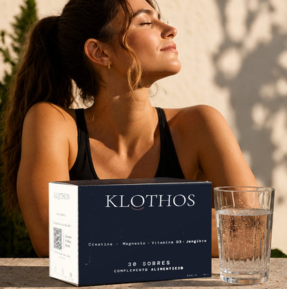 Mujer al sol con un vaso de agua; delante, la caja de KLOTHOS